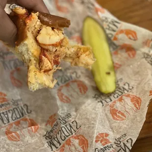 a hand holding a piece of bread and a pickle