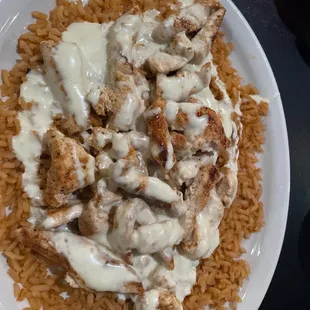 a plate of rice with chicken and gravy