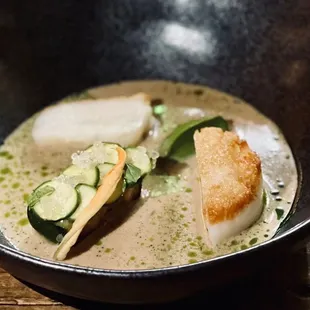 a bowl of soup with scallops and cucumbers