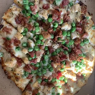 Chicken carbonara pizza. Weird and good. Alfredo sauce, chicken, bacon, peas.