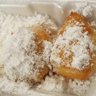 powdered sugar and powdered doughnuts in a styrofoam container