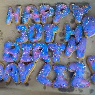 a box of blue and purple donuts with sprinkles
