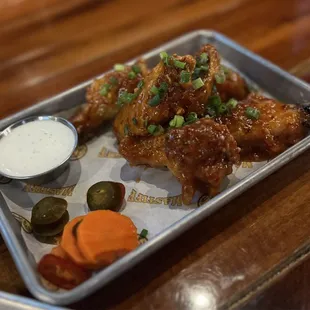 a tray of chicken wings with sauce and pickles