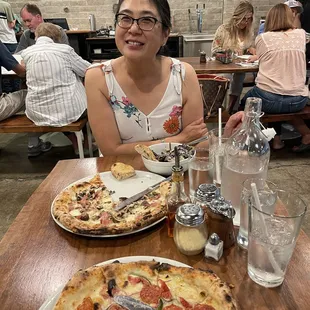 a woman sitting at a table with pizza
