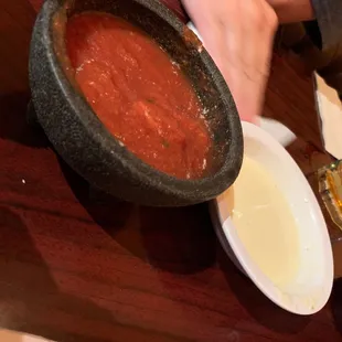 a bowl of tomato soup and a person holding a glass of beer