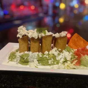 Delicious chicken flautas over a bed of guacamole.