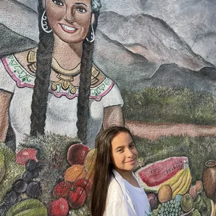 Admiring the bright colors and cultural representation in this mural.
