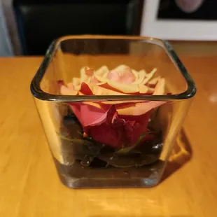 a rose in a glass bowl on a table