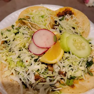 a plate of tacos with a variety of toppings