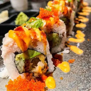 a sushi roll with salmon, avocado, and red cavia