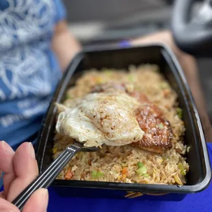 a person holding a fork and a tray of food