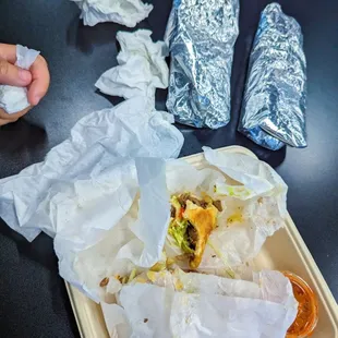 a tray of burritos and wrappers