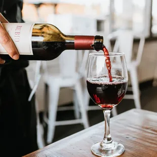 a person pouring a glass of wine