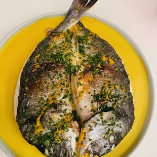 a whole fish on a yellow plate