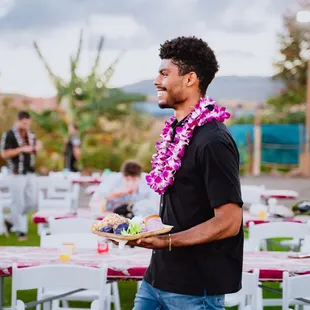 A guest strolls with a plate of flavorful cuisine at the luau, where every bite tells a tale of Hawaiian culinary delights