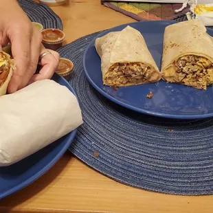 Breakfast burrito with eggs, bacon, potatoes, and cheese, and one with carne asada, eggs, beans, and cheese.