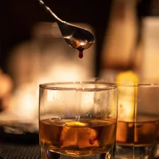 a glass of whiskey being poured with a spoon