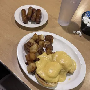 Eggs Benedict with potatoes and side of sausage.