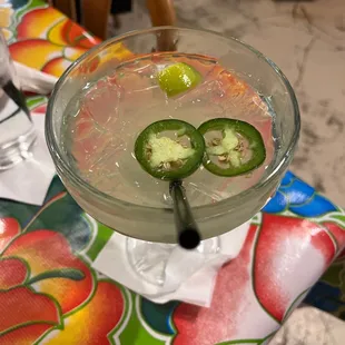 a glass with a drink and two slices of jalapenos