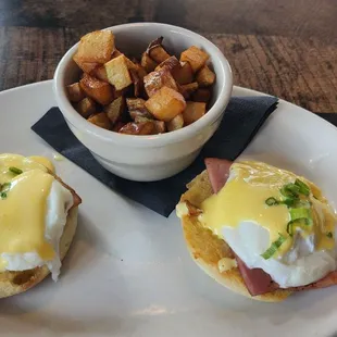 Eggs Benedict with hollandaise sauce, Ham, and english muffin with a side of home fries.