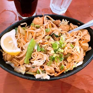 a bowl of noodles with a lemon wedge