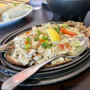 Bangus Sisig - marinated, fried, and diced milkfish, mixed with onions, peppers, and mayonnaise, served on a sizzling platter