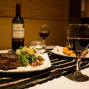 a plate of steak and a glass of wine