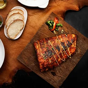 a wooden cutting board topped with meat and vegetables