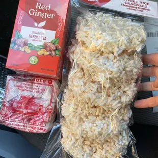 a hand holding a bag of rice and a packet of red ginger