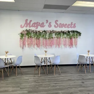 tables and chairs with flowers hanging from the wall