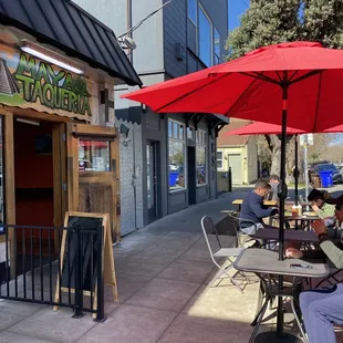 people sitting at tables under umbrellas