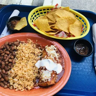 Chicken enchiladas with beans and rice alongside with nachos and salsa