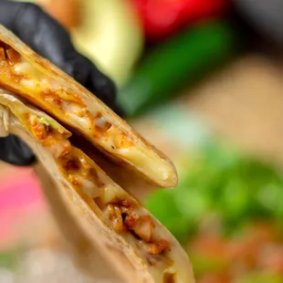 a hand holding a quesadilla