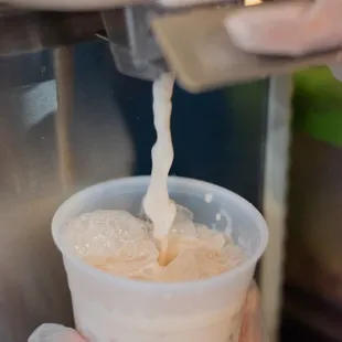 a person pouring ice cream into a cup