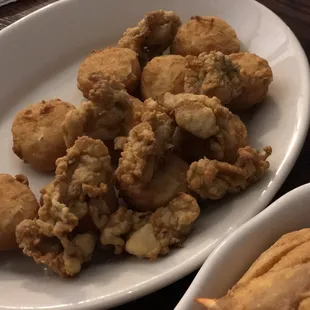 a plate of fried oysters and a bowl of dipping sauce