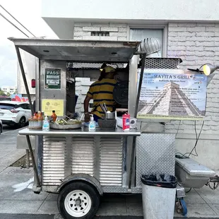 a man standing behind a food cart