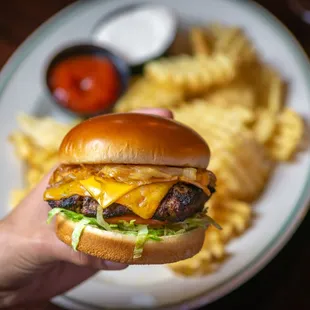a hand holding a cheeseburger