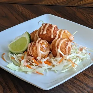 Our shrimp buñuelos are made with Yucca, served over a bed of cabbage salad, and garnished with your choice of mayokechu sauce.