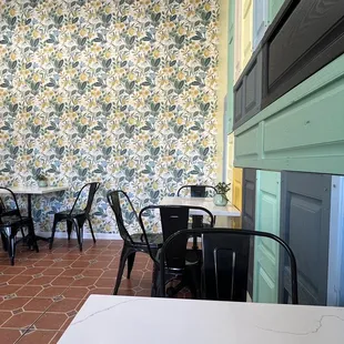 tables and chairs in front of a wallpapered wall