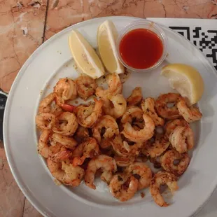 a plate of shrimp and lemon wedges