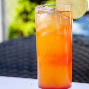 a glass of orange juice with a slice of lemon