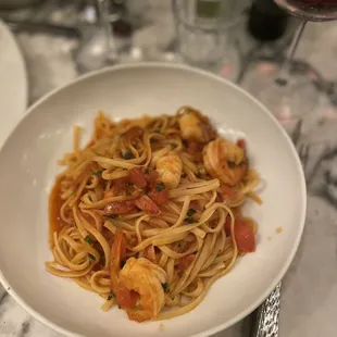 a plate of pasta with shrimp and tomatoes