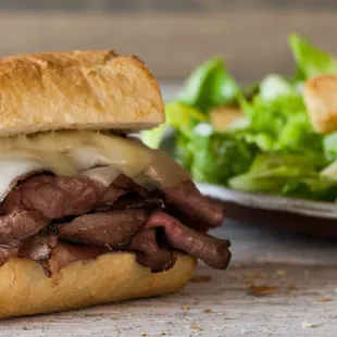 a steak sandwich with cheese and lettuce