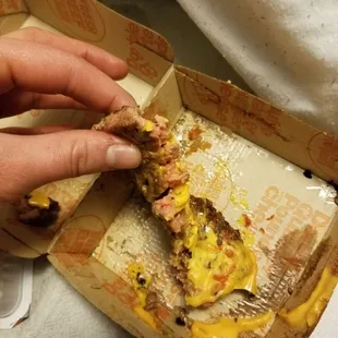 a hand grabbing a piece of food out of a box