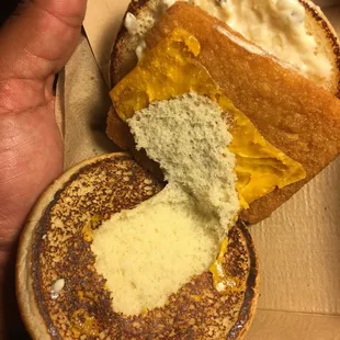 a hand holding a half eaten sandwich