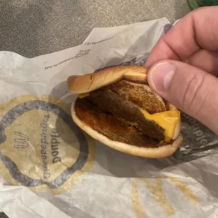 a hand holding a cheeseburger