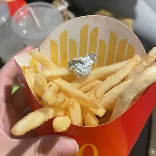 a hand holding a container of french fries