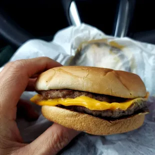 a hand holding a cheeseburger