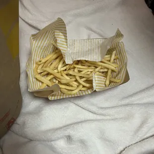 a basket of french fries on a bed