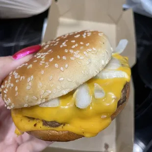 a hand holding a cheeseburger